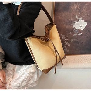 Detail view of large canvas bucket tote with brown leather trim and wavy edge design