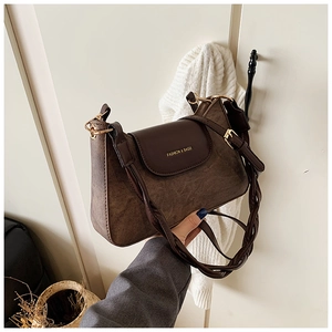 Detail of dark brown retro shoulder bag featuring woven strap and golden metal buckle