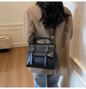 Vista posteriore di una borsa a tracolla vintage nera con doppia fibbia e tracolla sottile