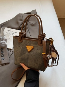 Vintage olive green canvas bucket bag with brown leather handles and a plush pompom charm