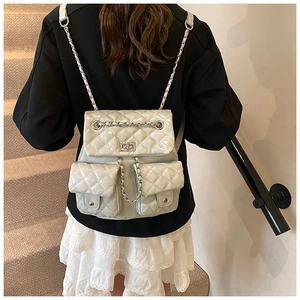 Detail view of glossy quilted backpack with silver chain straps and flap pockets