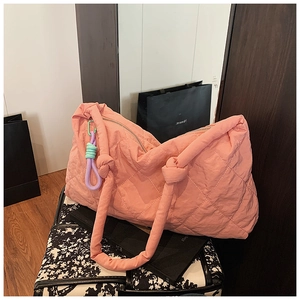 Detailed texture of pink quilted puffy tote bag with multi-color braided knot pendant