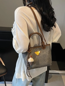 Women's marble grey bucket bag with brown leather handles and plush charm on model