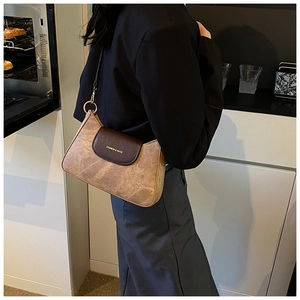 Close-up of vintage brown shoulder bag with a magnetic flap and fashion gold lettering