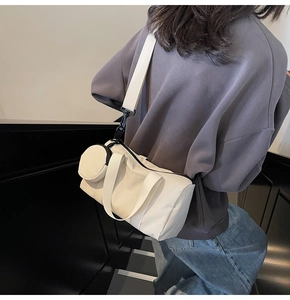 Détail du sac cylindrique en toile beige avec large bandoulière et petit porte-monnaie