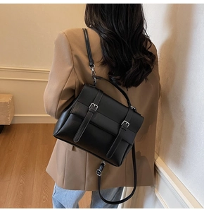 Dettaglio di una borsa messenger in pelle nera minimalista con fibbie in argento e tracolla
