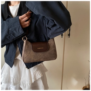 Close-up of retro brown shoulder bag with gold text print and elegant strap detail