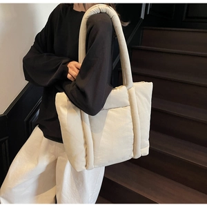 Borsa tote trapuntata bianco crema indossata a spalla da una modella sulle scale