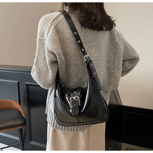 Glänzende schwarze Hobo-Tasche mit Metallschnalle und Ösenriemen an einem Model