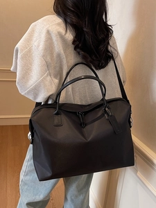 Large black nylon tote bag shown on a model, versatile travel bag with shoulder strap