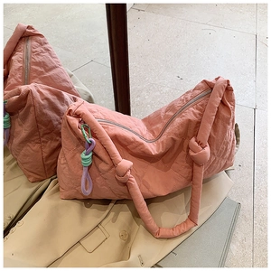 Detailed shot of pink quilted nylon hobo bag with knotted shoulder strap and colorful charm