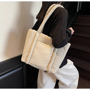 Dettaglio della borsa tote beige trapuntata con trama soffice e spalline imbottite