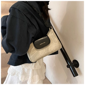 Detail of fashion square bag with black leather flap, gold hardware and printed text