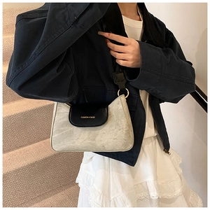 Detail of grey marble texture and black leather flap with golden ring buckle shoulder bag