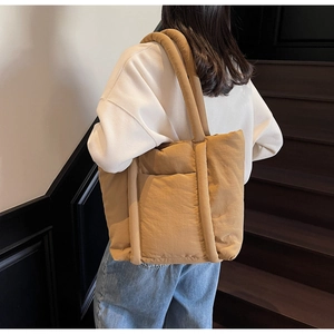 Dettaglio di una grande borsa tote trapuntata color kaki indossata da una modella