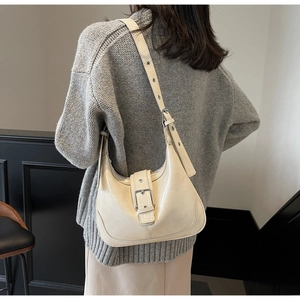 Detailansicht der cremefarbenen Hobo-Tasche mit Silberschnalle und verstellbarem Riemen