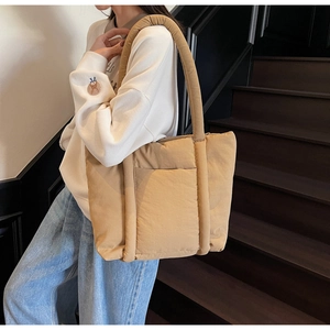 Vista laterale dettagliata della borsa tote trapuntata beige con i manici imbottiti