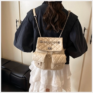 Detail of cream quilted leather backpack with silver turn-lock and chain straps