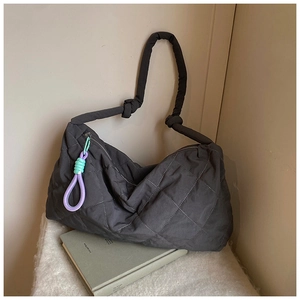 Detailed shot of dark grey quilted tote bag featuring a decorative woven lanyard and knots