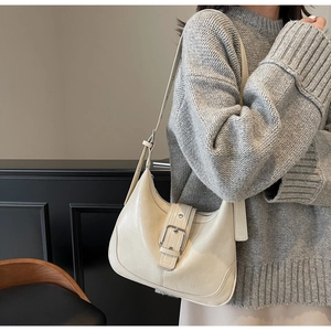 Detail der beige Hobo-Tasche mit Metallschnalle und verstellbarem Riemen am Modell