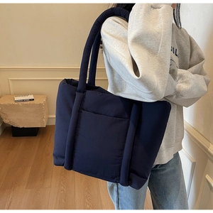 Dettaglio della borsa tote trapuntata blu navy con manici imbottiti e tasca esterna