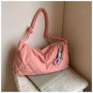 Detail of dusty pink puffer tote bag with quilted texture and colorful rope zipper pull