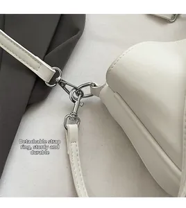 Detail view of silver detachable hooks and sturdy stitching on white crossbody bag