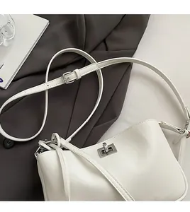 Close-up of white minimalist leather crossbody bag with silver rotating metal lock
