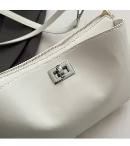 Detailed macro view of white leather shoulder bag with silver metal swivel lock and zipper