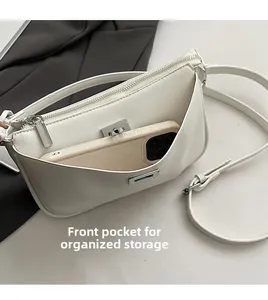 Detailed view of white leather crossbody bag with front pocket showing phone storage space