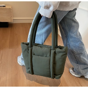 Dettaglio della borsa tote trapuntata verde scuro con manici imbottiti sulla spalla
