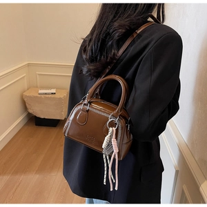 Detailed back view of a dark brown glossy Boston bag with white zigzag stitching
