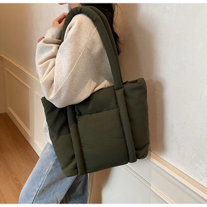 Borsa tote trapuntata verde oliva con manici imbottiti indossata sulla spalla