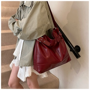 Detail view of large burgundy oil wax leather tote bag worn by model on shoulder