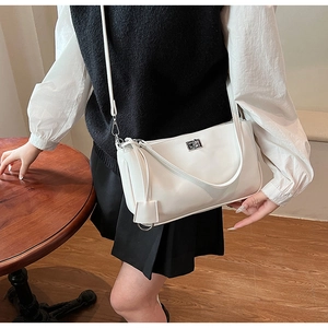 Detail of a minimalist white leather crossbody bag featuring a silver metal twist lock clasp