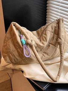 Quilted khaki tote bag with large capacity and decorative rope charm in lifestyle setting