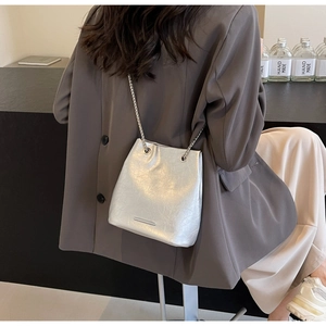 Detail of silver metallic chain strap and wrinkled leather texture on bucket shoulder bag