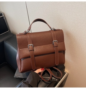 Dettaglio dello zaino vintage in pelle marrone con doppie fibbie argentate e manico superiore