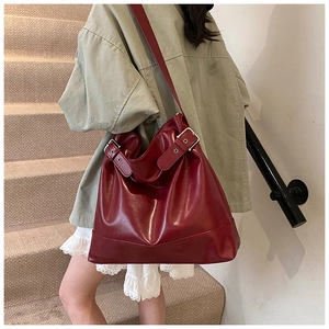 Burgundy tote bag detail showing adjustable shoulder strap with metal buckles on leather