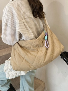 Minimalist khaki quilted tote bag with a contrast purple woven knot charm on the strap