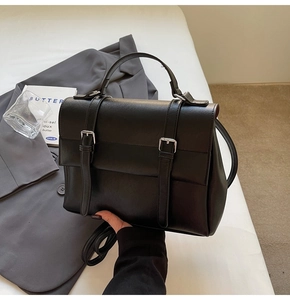 Macro view of matte black leather briefcase detail with silver metal buckles and straps