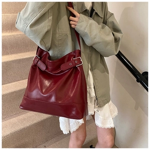 Detail view of burgundy leather tote bag with silver buckle strap and reinforced bottom