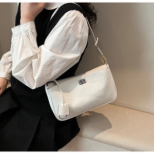 Detail of white baguette bag with silver twist lock and decorative charm pendant