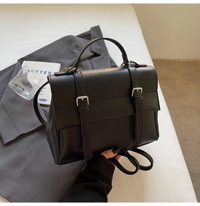 Dettaglio borsa a mano in pelle nera opaca con fibbie argentate e tracolla regolabile