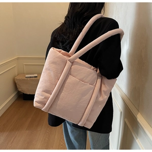 Dettaglio della trama trapuntata e tasca esterna su una grande borsa tote rosa puffy