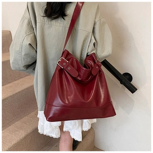 Detail of burgundy leather tote bag with silver buckle straps and glossy texture
