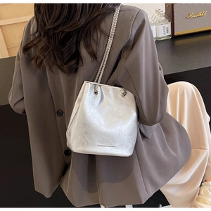 Detailed view of silver metallic bucket bag featuring pleated texture and chain straps