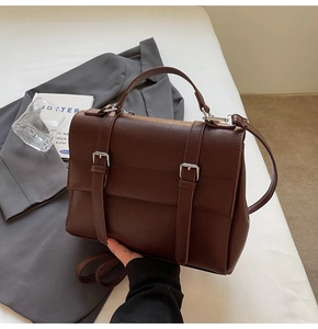 Close-up of vintage brown leather satchel with silver buckles and handle details