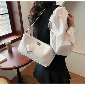 Close-up of a white leather underarm bag with silver twist lock and square charm detail