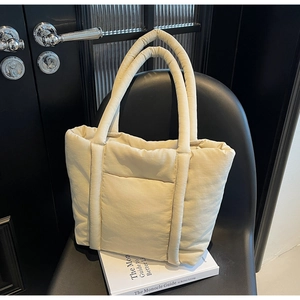 Dettaglio della borsa tote trapuntata beige su sedia in pelle nera dallo stile moderno